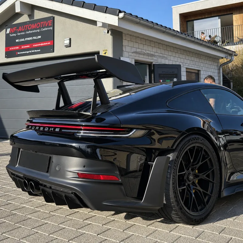 Schwarzer Porsche mit Heckflügel vor NF-Automotive in Rheineck